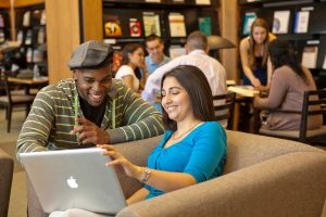 two students study together over a laptop in the library