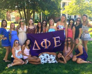 Students of DPhiE stand in front of a purple banner with their Greek letters