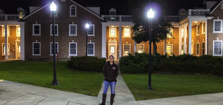 Student stands in front of dorms