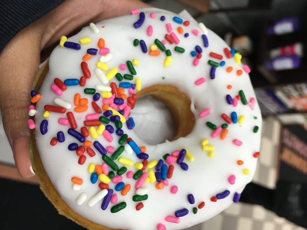 donut with white icing and rainbow sprinkles
