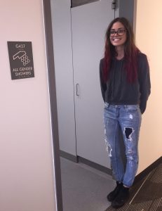 Caroline stands near all gender bathrooms in Holly Pointe