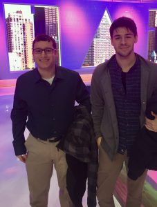 two male students stand in front of the Harry Connick Jr. Show stage