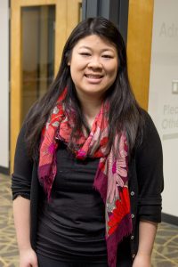 student stands for a portrait, wearing a black shirt and red scarf