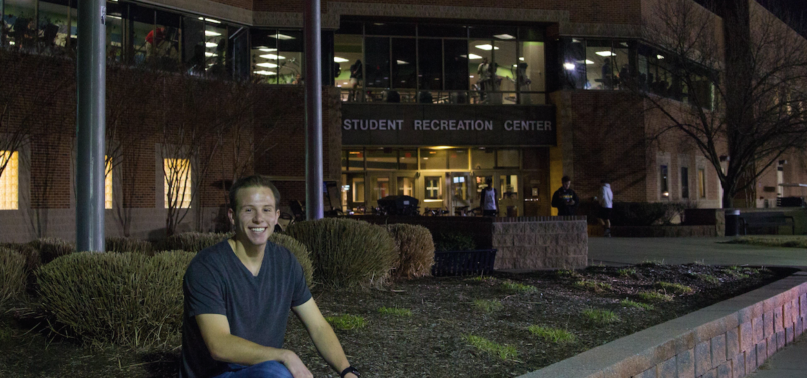 student sits outside rec center