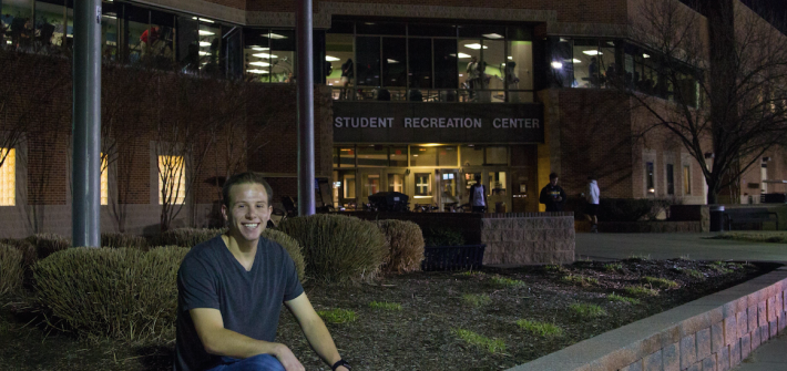 student sits outside rec center