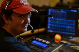 student lighting director looks at camera with computer in front of him