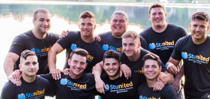 group of students wear club t-shirts, huddled in a group