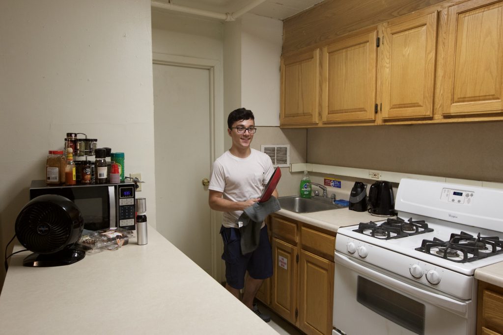 Anthony dries a pot in his kitchen