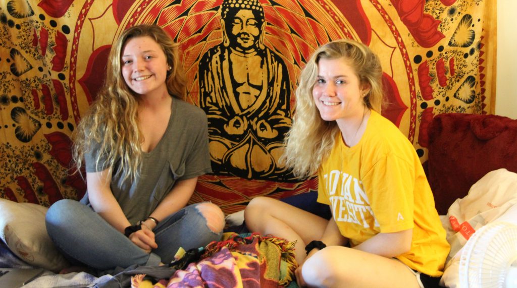 Freshman Kaylin Logan (left) with her friend Mallory Manz pose in front of Kaylin's tapestry.