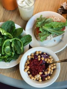 A student's meal of spinach and peppers, a tuna sandwich with tomato and lettuce, and quinoa with vegetables sits on a table in the Marketplace