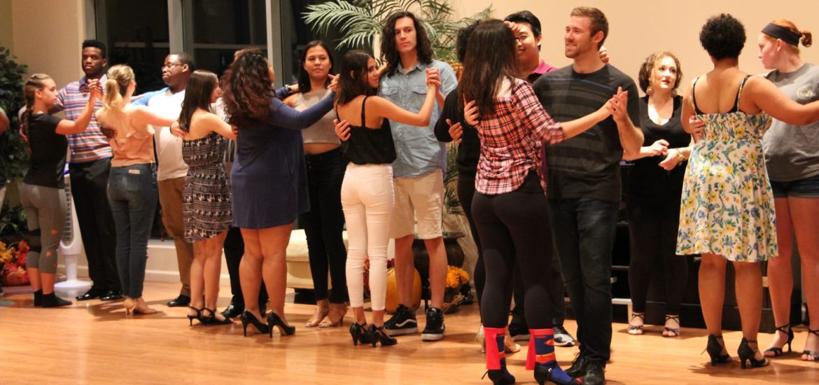 Ballroom dance club members stand facing their partners in the ballroom