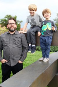 Shane and two sons standing on statue at Robinson Hall 