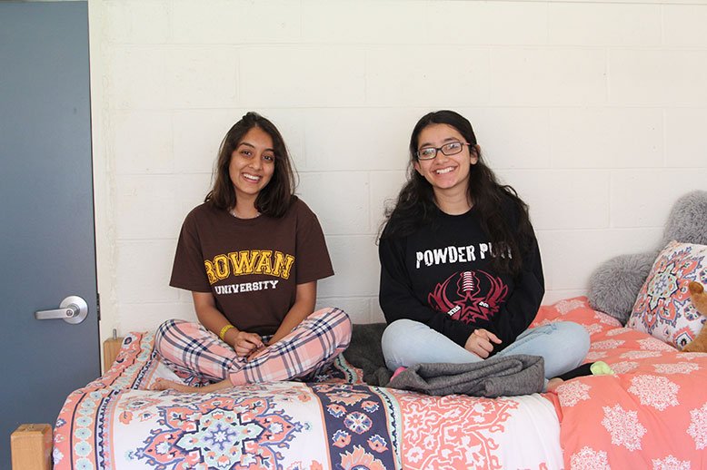 Nidhee, left, and Vaishnavi, right, sit on Vaishnavi's bed and laugh.