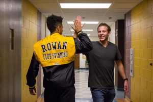 two friends high five each other while walking past each other