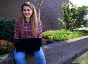 Alexa on her laptop outside of Wilson Hall at Rowan University