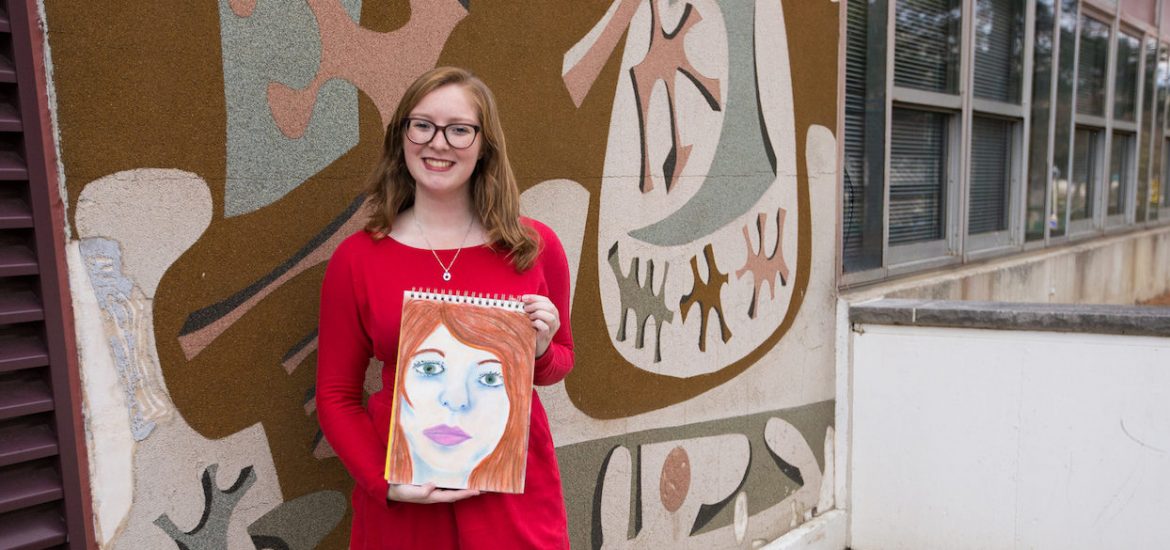 Rowan student Melissa holding her drawing outside Westby art building