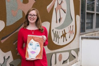 Rowan student Melissa holding her drawing outside Westby art building
