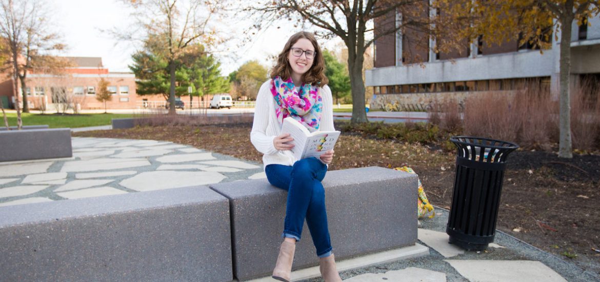 Rowan student Chrissie outside of Robinson Hall reading a book