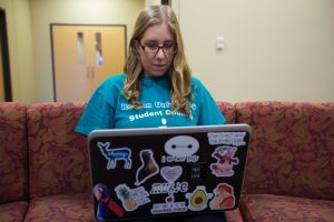 Rowan student typing on her laptop on Rowan campus inside James Hall 