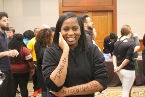 A student standing with her quote written on her arms smiling for her photo.