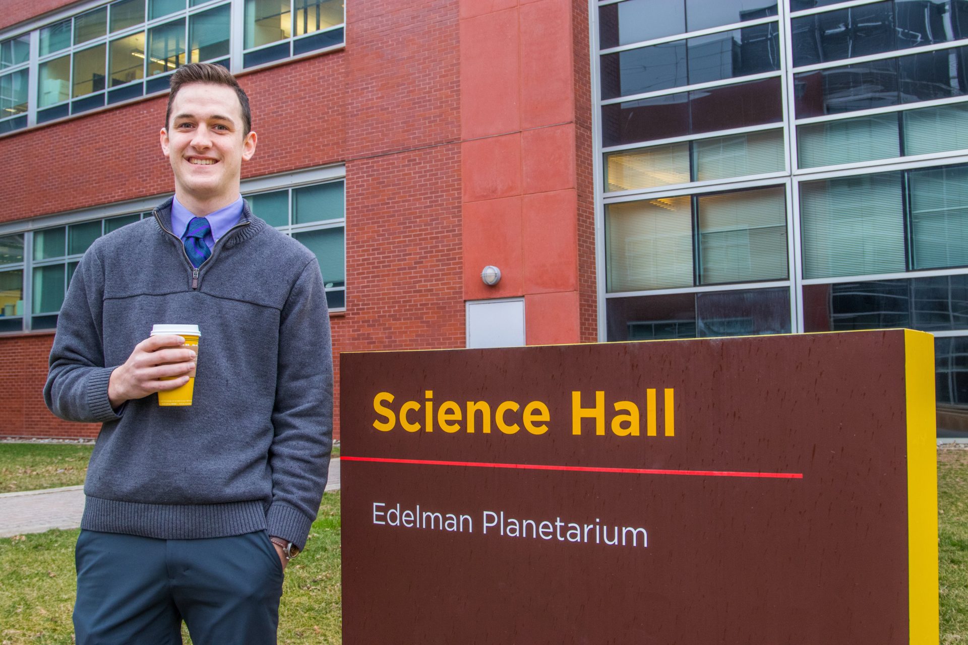 Andrew Milcarek, a Translational Biomedical Sciences major at Rowan University, stands outside Science Hall with a cup of Peet's coffee.