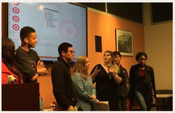 A group of students stands in front of a Target presentation with a microphone during the Leading Through Change event held by the Office of Career Advancement at Rowan University.