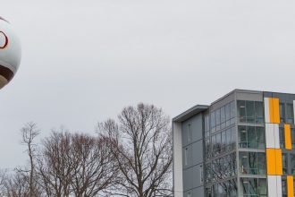 orange gray and white Holly Pointe Commons at Rowan University with Glassboro water tower in view