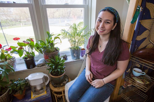 Noel sits by her window in Willow Hall at Rowan University, surrounded by plants