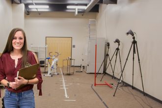 female student in hallway surrounded by pt equipment