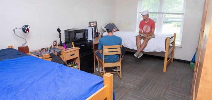 Two roommates play video games together in their room.