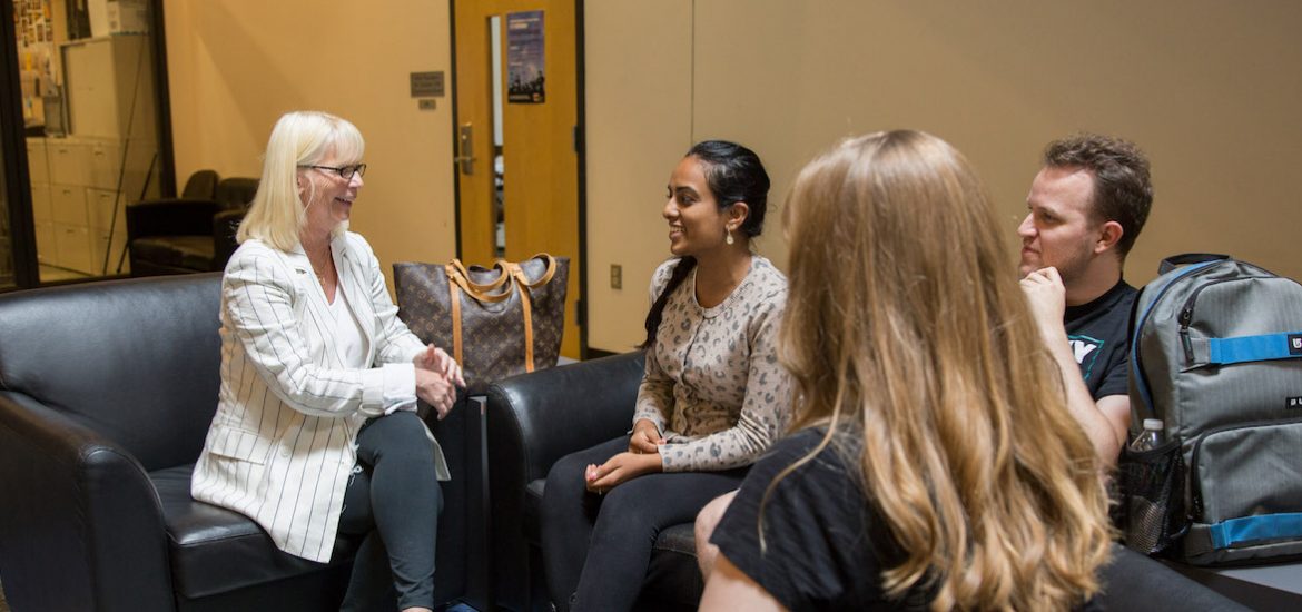 Rowan University Professor Kathy Balin sitting in Savitz hall chatting with 3 students