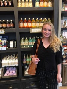 Rowan University's Nicole smiles broadly in front of a display of beauty items at her internship