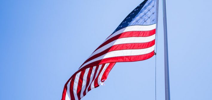 American flag waving in sunshine with blue sky in background