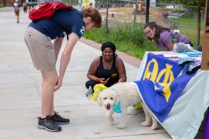 students smile with a dog at the organization fair