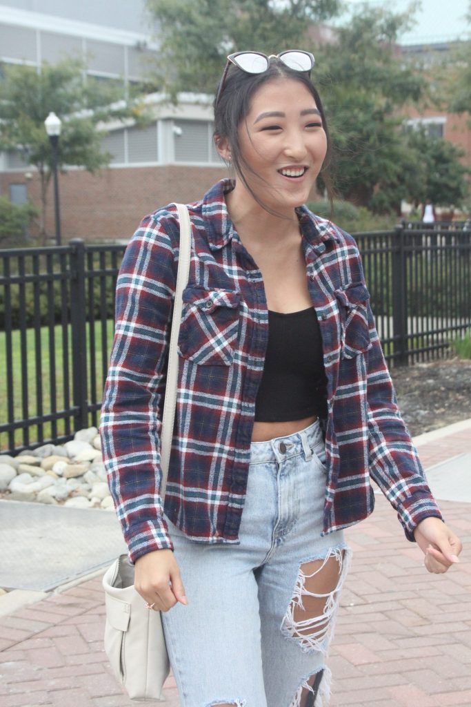 Rylee standing outside wearing a red, white and blue plaid long sleeved shirt