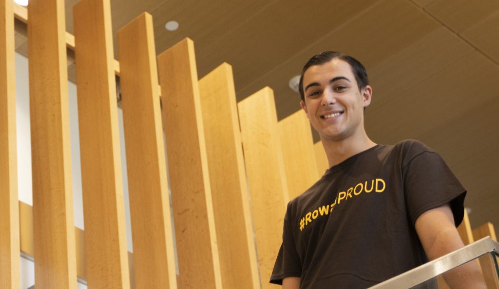 Dan Ryan stands in his "Rowan Proud" shirt on the stairs in the Business Hall at Rowan University.