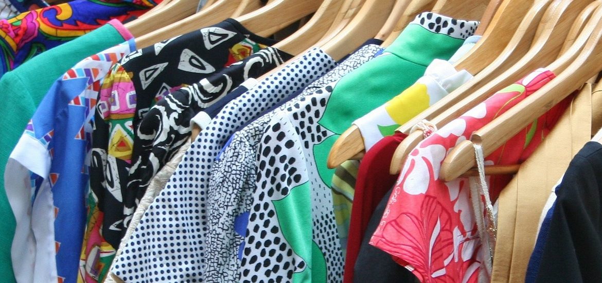 close up of shirts with variety of patterns and colors hanging on hangers in a closet