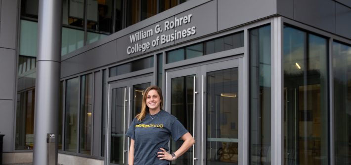 Rachel outside business building with silver sign in background saying Rohrer College of Business