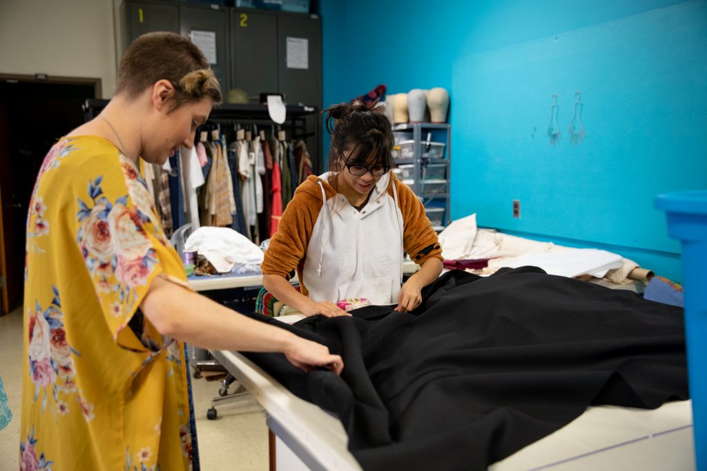 Jamie and a student working on pinning black curtains