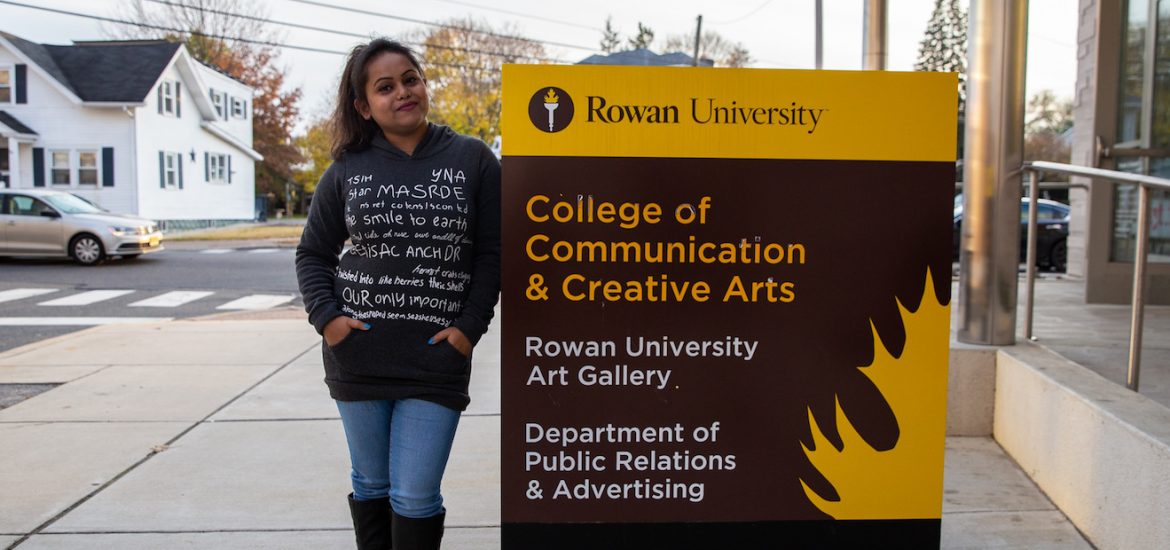Aysha outside College of Communication and Creative Arts sign