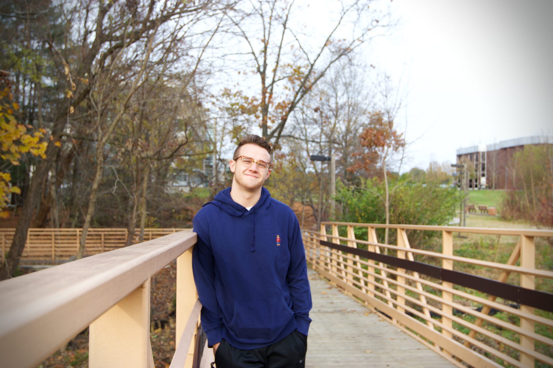 Rowan student, Eric, posing on bridge over a campus river.