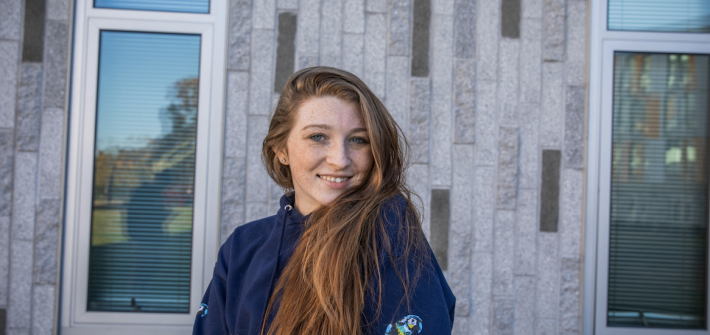 Kallie stands facing camera head turned over shoulder, with long hair down to her waist