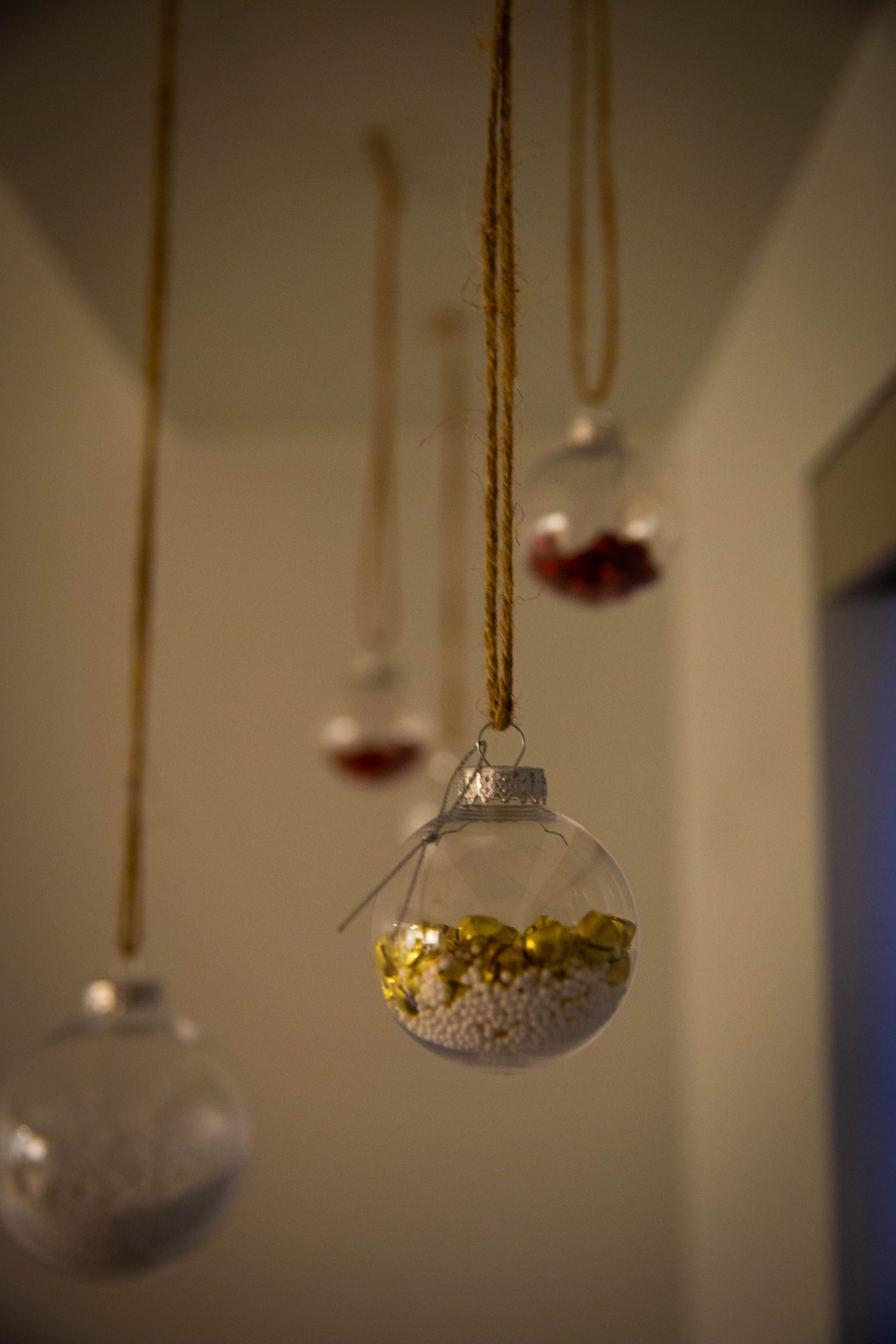 Photo shows finished DIY ornaments hanging from living room ceiling.