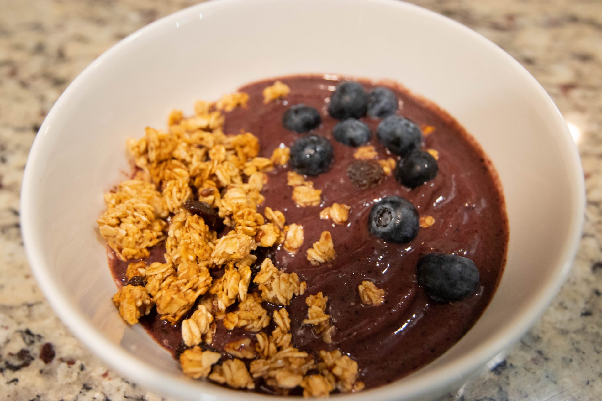 Up-close shot of smoothie bowl topped with granola and blueberries.