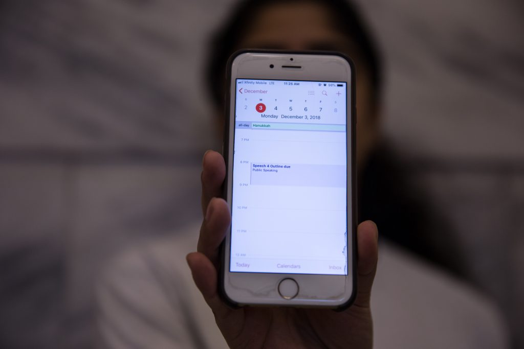 A student holds her reminder list app on her phone up to the camera