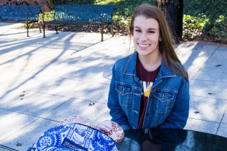 Skylar sits outside the student center at a solar panel powered bench