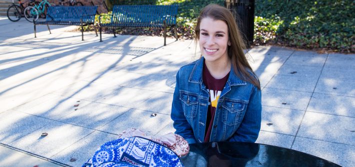 Skylar sits outside the student center at a solar panel powered bench