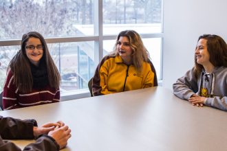 Liz and her friends sitting upstairs in Savitz hall by a snowy window