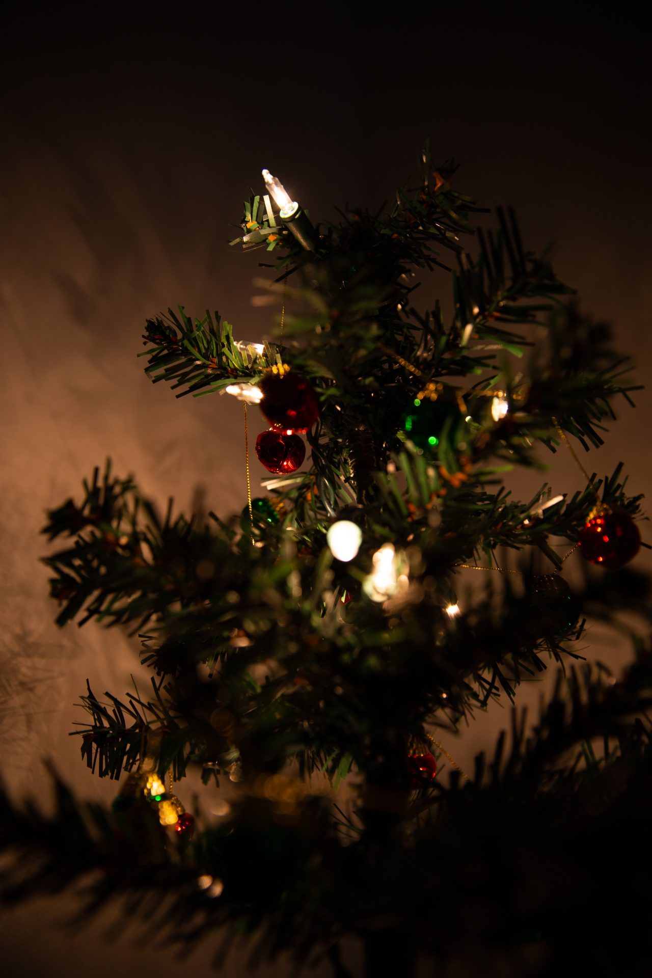 Photo shows the $1 Christmas tree decorated with string lights and tiny ornaments.