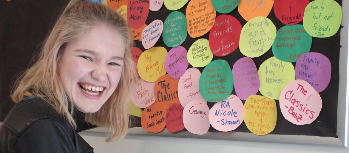 Nicole Grant laughs as she stands in front of a colorful bulletin board she made as a resident assistant.